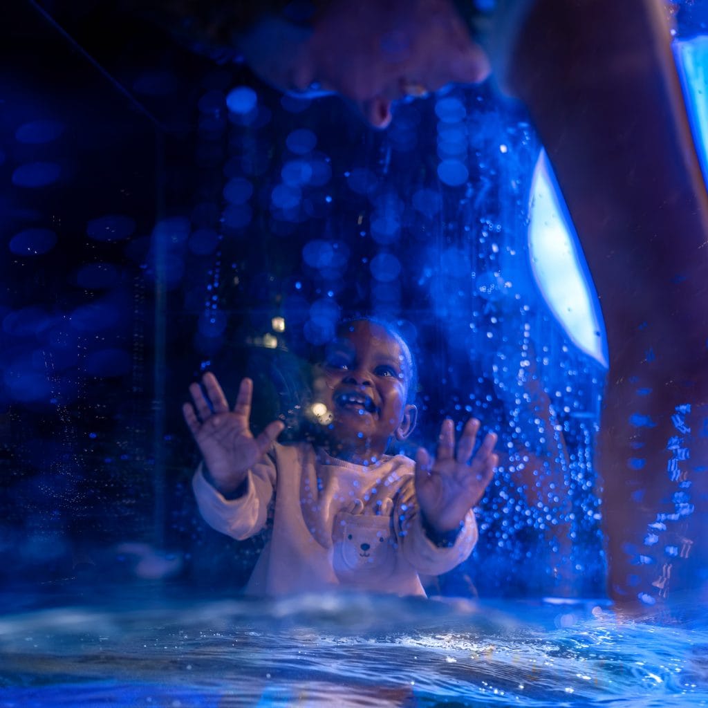 Image of baby looking into water tank in which there is a dancer