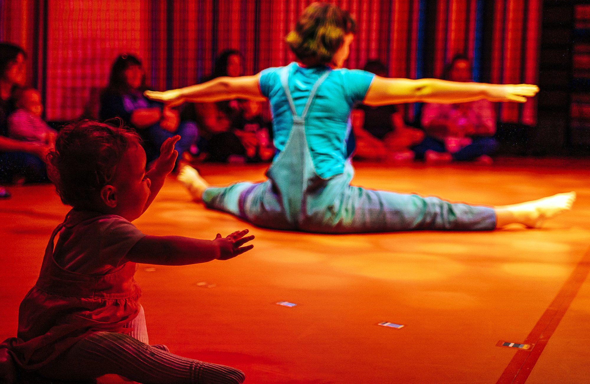 Young baby copies artist's movements while sitting on the floor during a performance of Little Top