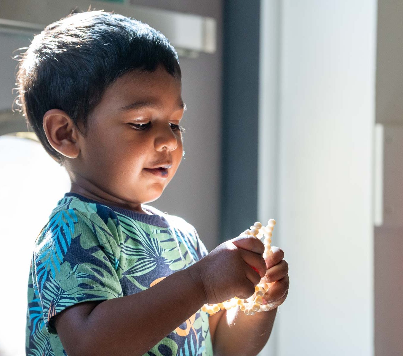 A young boy looking at a light in his hands